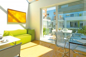Wohnzimmer mit Essbereich und Arbeitsplatz sowie Zugang zum Balkon in einer Studentenwohnung der Wohnanlage studiosus 3 in München Moosach